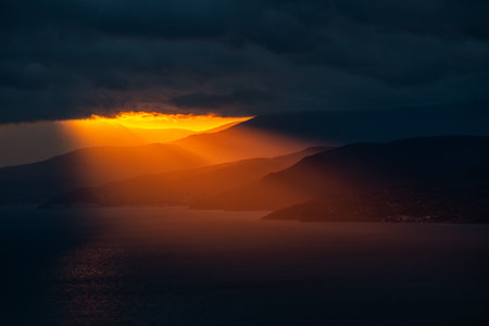 The last rays through the dark clouds at sunset illuminate the southern coast of Crimeaの写真素材