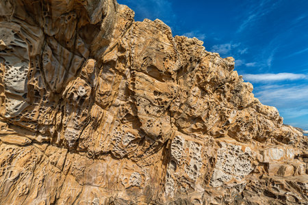Sandstone cliff with honeycomb weathering n blue sky backgroundの写真素材