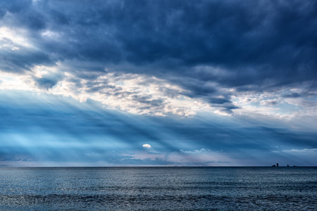 Diagonal sun rays under dark clouds over the Black sea in Crimeaの写真素材