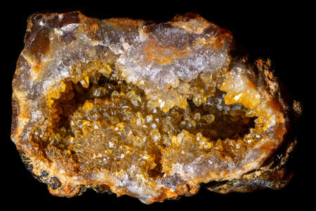 Half of a geode with quartz crystals colored yellow by iron oxides on a black background