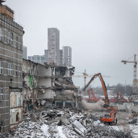 Demolition of an old industrial building in Moscow on a overcast winter day with a new high-rise residential building in the backgroundのeditorial素材