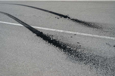 Close-up view of burnt rubber tracks on the asphalt with white markings.の写真素材