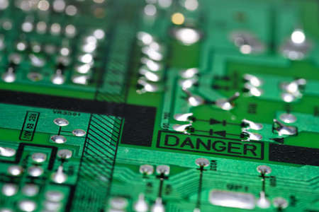 An old green printed circuit board with a "danger" inscription.の写真素材