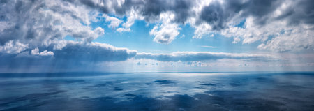 Clouds over the sea on a summer day with sunbeams, horizontally panoramic.の写真素材