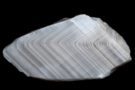 A sample of white striped zonal calcite, isolated on a black background.の写真素材