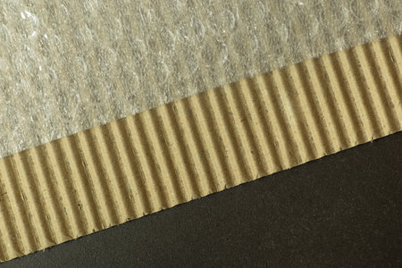 Corrugated cardboard box with bubble wrap photographed on dark stone background with diagonal gradientの写真素材