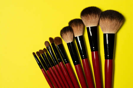 Top horizontal view of set of red makeup brushes on yellow backgroundの写真素材
