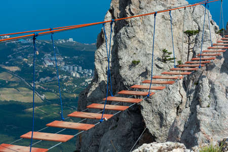 Red suspension fragile bridge with wooden construction on the top of the mountain. Concept of...