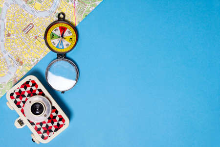 Blue background with colorful compass, map and retro style film camera. Abstract background with...