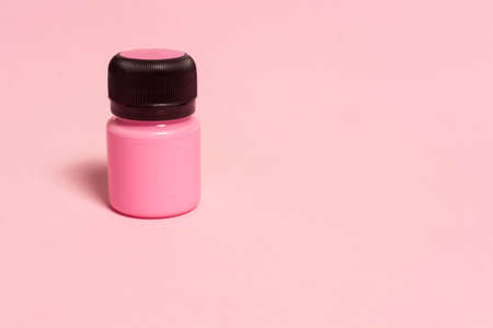 tin of pink color acrylic paint on pink background with copy space for your text.