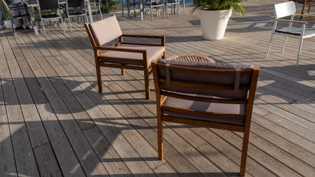 Wooden table and chairs on the summer terrace during sunshine weather.