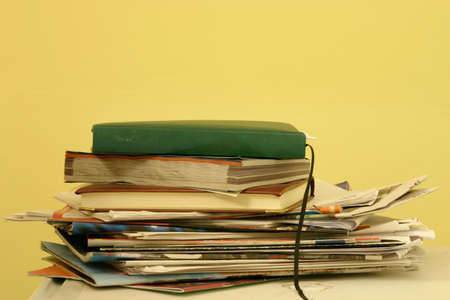 A stack of old magazines and diaries on a white table with a yellow background, with space for...
