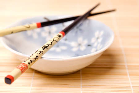 Chinese chopsticks on a soup bowl and bamboo matの写真素材