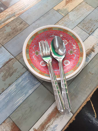 Chinese style spoons, forks, and dishes on a wooden table.の素材
