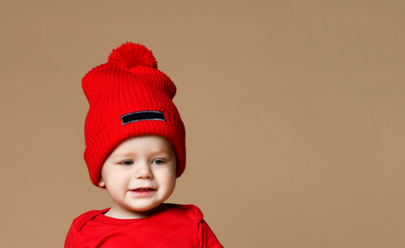 Smiling baby toddler boy in knitted hat over nude beige backgroundの写真素材