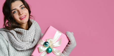 Beautiful young woman in warm sweater and mittens, holding paper gift box. isolated portrait. Bannerの写真素材