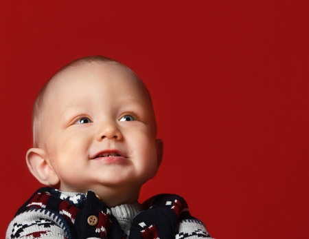 Funny little baby wearing warm knitted Christmas sweater at studio on cold winter day. it is snowing