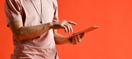 Human hands using tablet computer over orange wall studioの写真素材