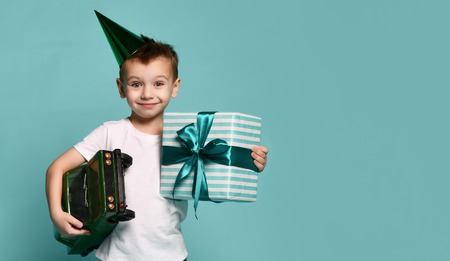 little boy holds a toy car and a box with a gift on a light background. birthday partyの写真素材