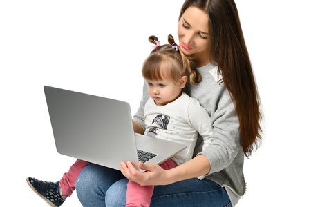 happy mother with adorable little girl with laptop . childhood, parenting and technology concept . isolatedの写真素材