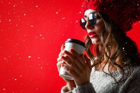 winter, people, happiness, drink and fast food concept - woman in hat with takeaway tea or coffee cup, side viewの写真素材