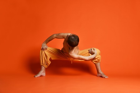 Athletic muscular senior man working out, yoga, pilates, fitness training, doing sumo squat exercises, revolved temple, goddess, sumo wrestler poseの写真素材