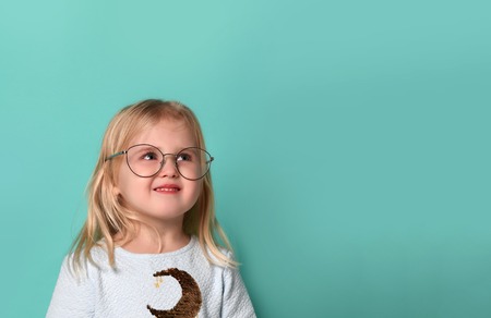 Thinking kid girl in glasses looking happy. Closeup effect portrait