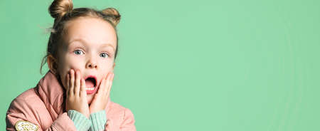 surprised girl cute little girl with bagel hairs looking at the camera waryly, holding her face with...