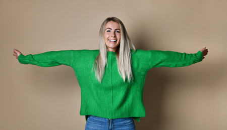Young woman arms outstretched by studio wall enjoying freedom and life.の写真素材