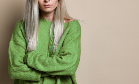 cropped Portrait of an upset unsatisfied woman standing with arms folded and looking away isolated over beige backgroundの写真素材