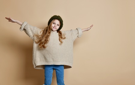 Winter portrait of happy little girl wearing knitted green hat and sweater. Child on lighten...