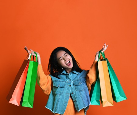Young woman with shopping bags on color background