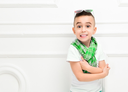 Fashion beautiful little boy in bright pants and t-shirt and scarf and sunglasses over white background,. Fashionable childrenの写真素材