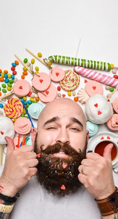 Happy bearded man biting cream cake isolated on white backgroundの写真素材