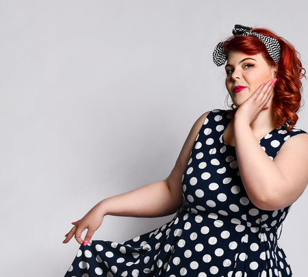 Portrait of a cute Beautiful retro full fat woman in polka-dot dress with red lips and manicure nails and old-style haircut. Pin up a female portrait.の写真素材