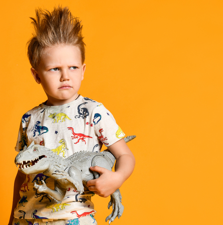 little boy with a funny, disheveled hair holds the toy plastic dinosaur as a portrait. Boysの写真素材