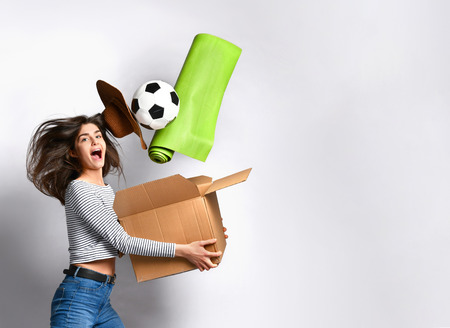 woman is infinitely happy to move to her new dream home. She jumps for joy holding a cardboard box...