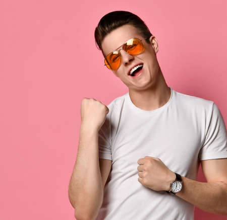 Winner celebrates. Great success. Joyful young man in glasses with a happy facial expression on a...