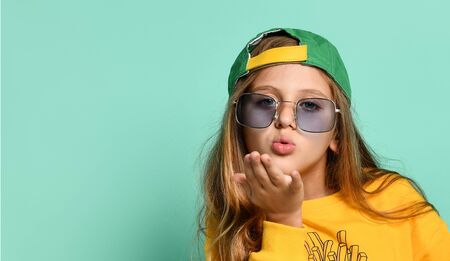 Beautiful young girl teenager in stylish glasses and a cap, dressed back to front in front sends a...