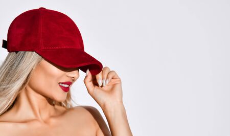 Gorgeous well-groomed blonde with red lipstick on her lips hides her eyes under a chelvet red capの写真素材