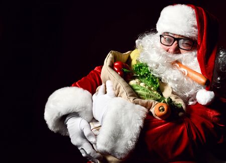 Jolly Santa Claus is holding a big sack full of fruits and vegetables. Enjoy a healthy Christmas dinner. Healthy Christmas Recipes. Christmas diet.の写真素材