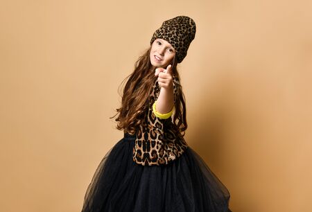 Young plus size girl model in stylish leopard colored casual clothing and black skirt standing and pointing at camera over yellow wall background. Trendy youth fashion conceptの写真素材