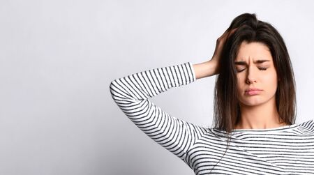 Upset tired girl holds hand to head, headache, migraineの写真素材