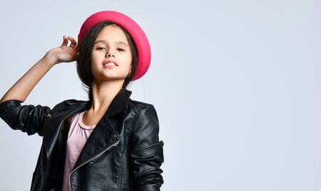 portrait Brunette teenage kid in black leather jacket and pink hat . She smiling while posing standing isolated on white. Hipster style, fashion, beauty.の写真素材