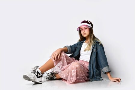 excited jump girl in stylish casual clothes, sunglasses and sneakers sitting and looking at you over...