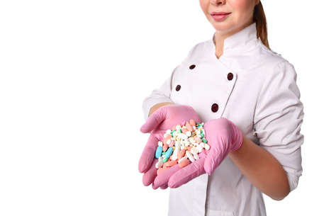 Cropped view of unknown female doctor or nurse in medical gown and gloves holding handful of tablets...