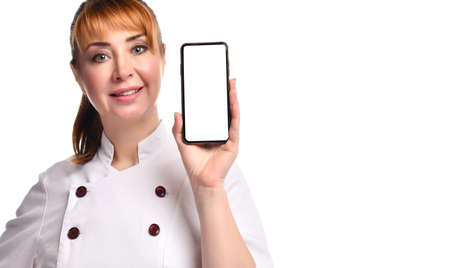 Smiling female doctor in medical gown looking forward while showing at camera smartphone with white screen for mockup. Close up isolated on white, copy space. Nurse, first aid, health care, technologyの写真素材