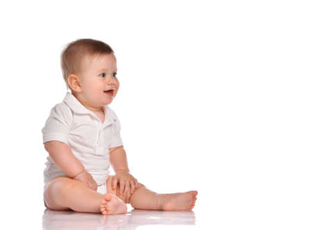 Cute little boy in white overalls, baby toddler sitting and happy looking at the corner, isolated on whiteの写真素材