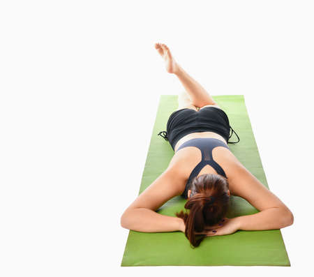 athlete girl lies on her stomach and does exercises on the back surface of the muscles of the legs, doing leg swings.の写真素材