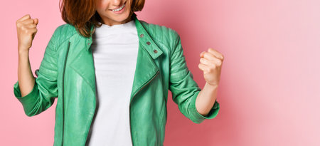 Beautiful young woman happy and excited expressing winning gesture. Successful and celebrating victory, triumphant, pink backgroundの写真素材